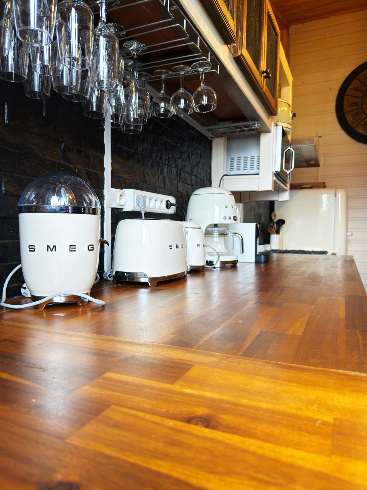Détail de la cuisine du Chalet Des Sens à Cilaos : électroménager Smeg, verrerie suspendue et plan de travail en bois massif