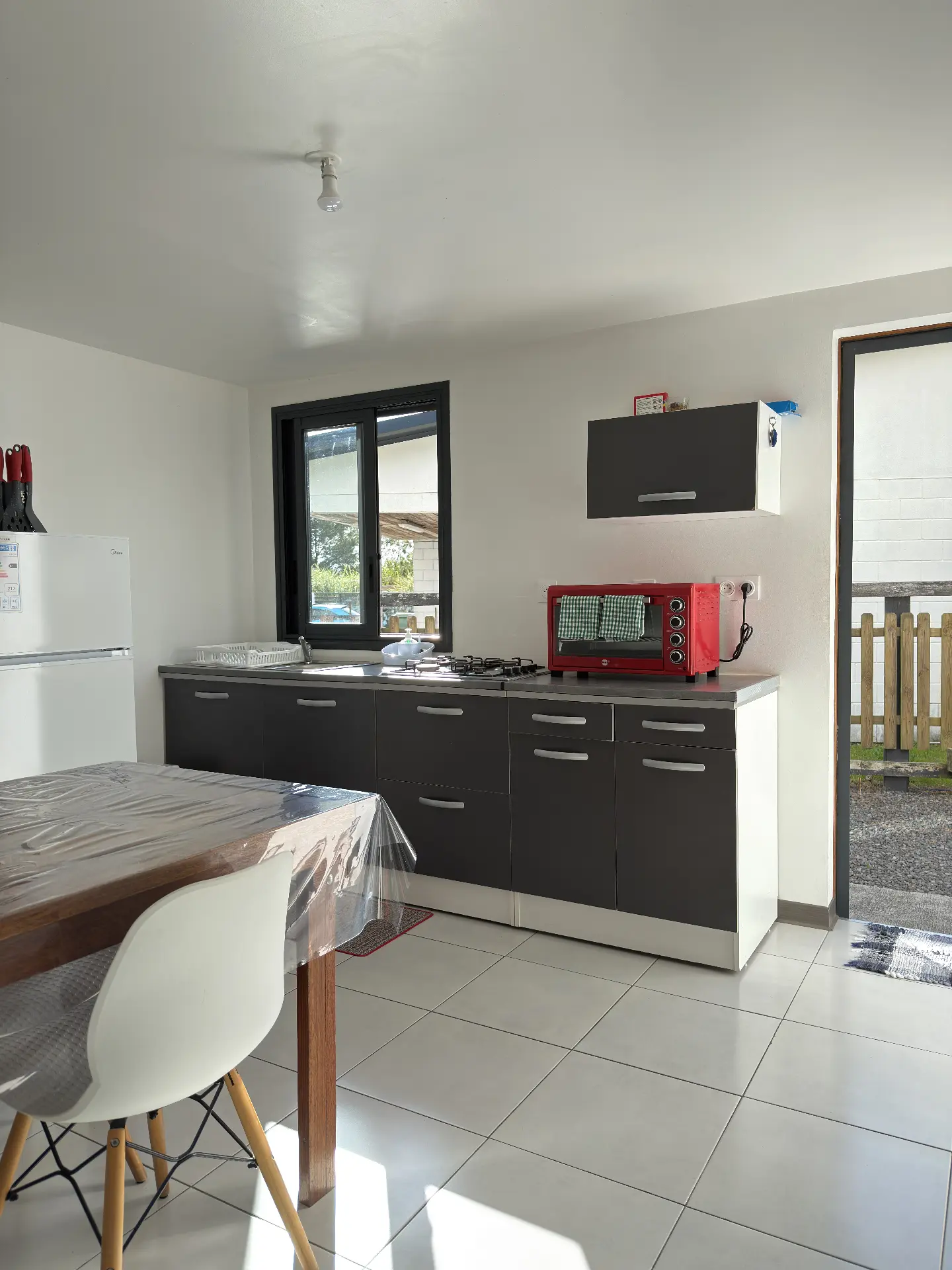 Cuisine équipée de La Caz'à Chisy à Bras-Sec avec plaque de cuisson, four, réfrigérateur et accès à la terrasse