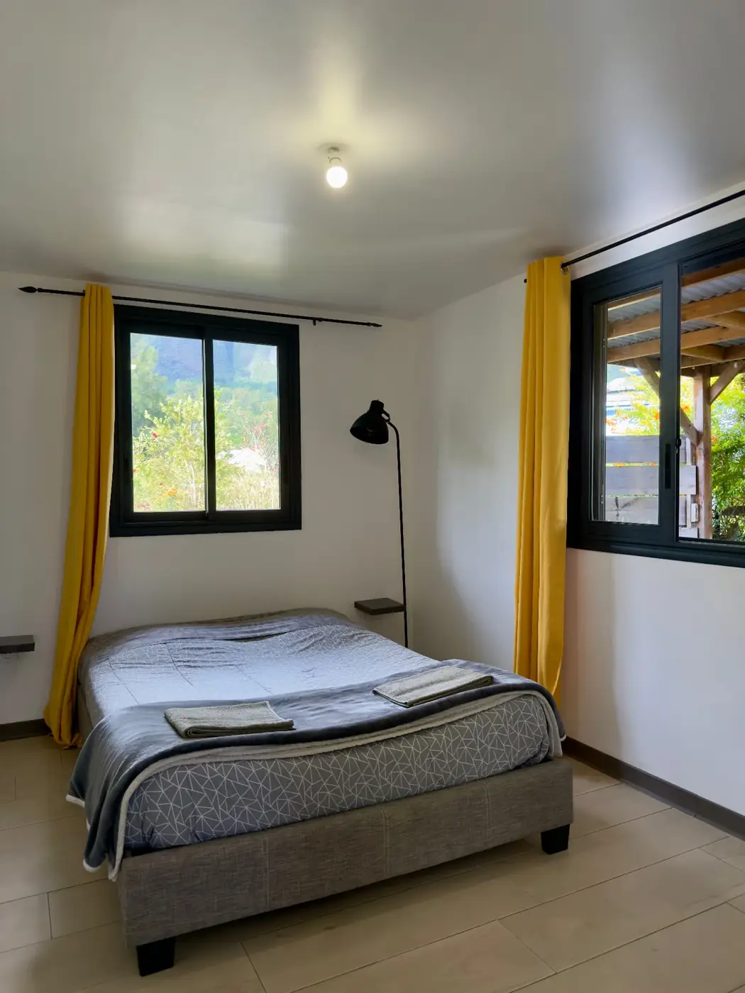 Première chambre double de La Caz'à Chisy à Bras-Sec, lit double, rideaux jaunes et vue sur les reliefs de Cilaos