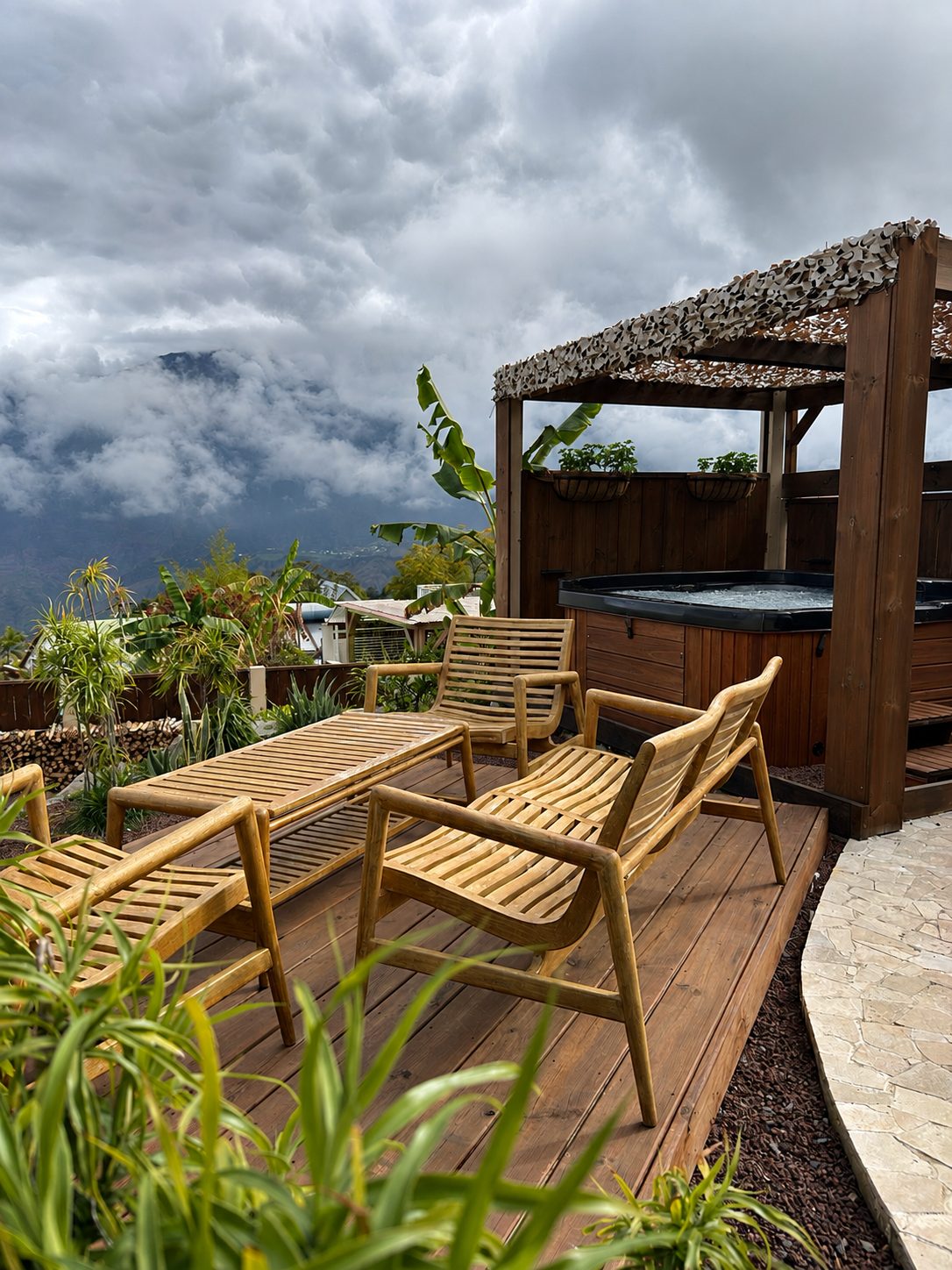 Terrasse en bois du Chalet Des Sens à Cilaos avec salon de jardin en teck et jacuzzi, vue sur les montagnes