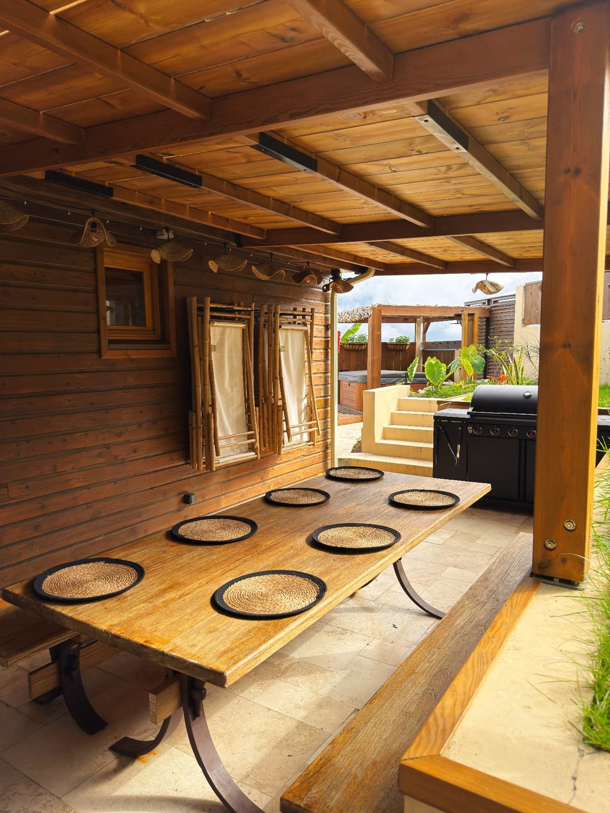 Table à manger extérieure du Chalet Des Sens à Cilaos sous pergola, avec barbecue et accès au jacuzzi
