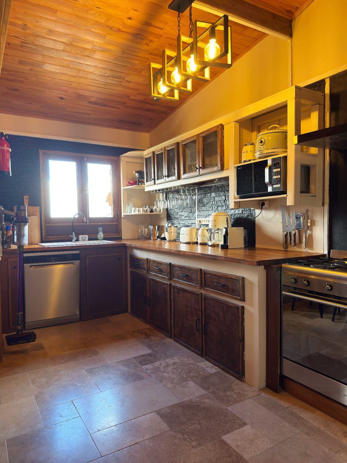 Cuisine équipée du Chalet Des Sens à Cilaos avec plan de travail en bois, piano de cuisson et électroménager Smeg