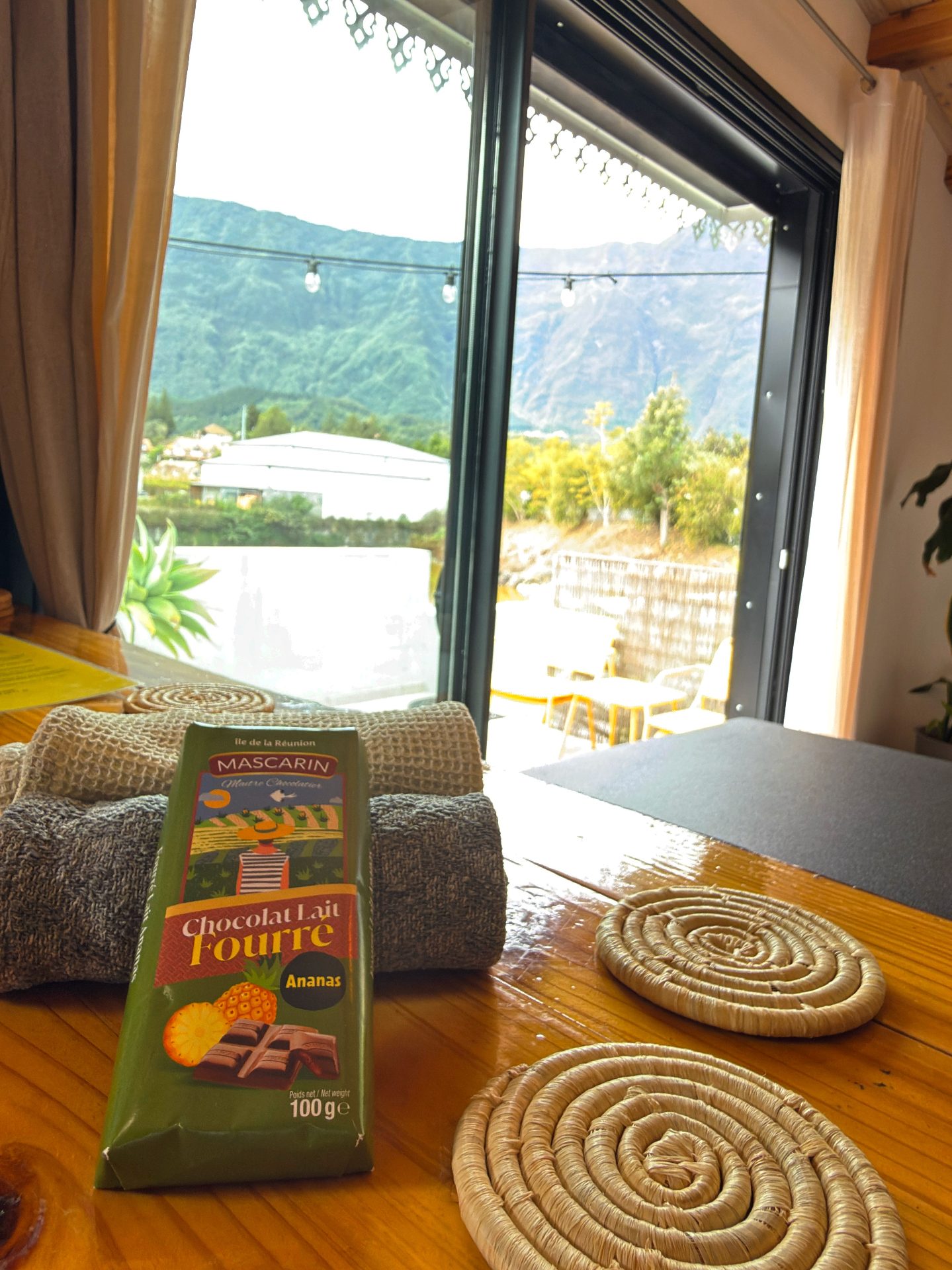 Attention d'accueil au bungalow Le Poule d'Eau à Cilaos — chocolat local Mascarin et linge de toilette posés face aux montagnes du cirque