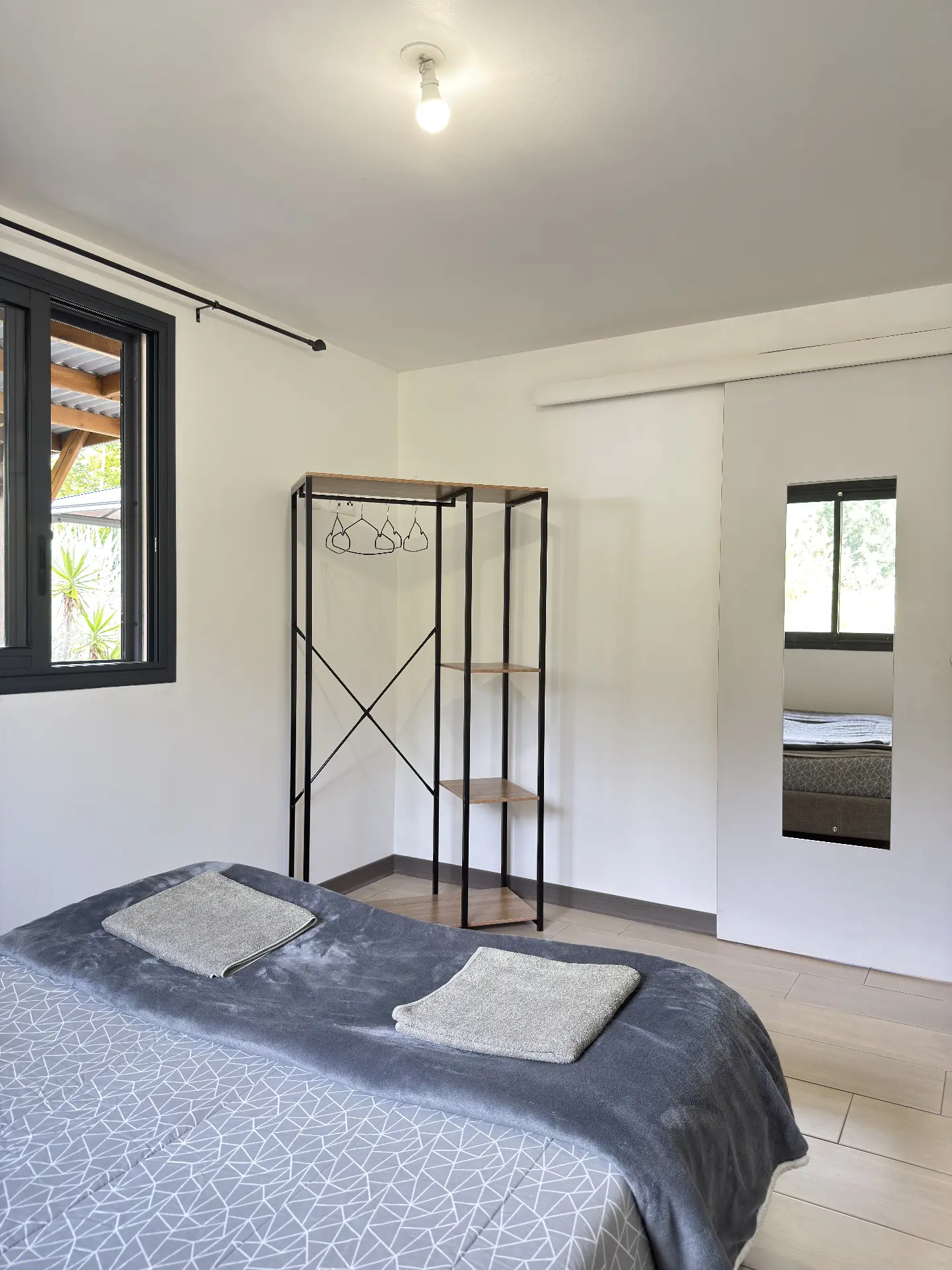 Vue d'ensemble de la première chambre de La Caz'à Chisy avec penderie ouverte et linge de toilette fourni