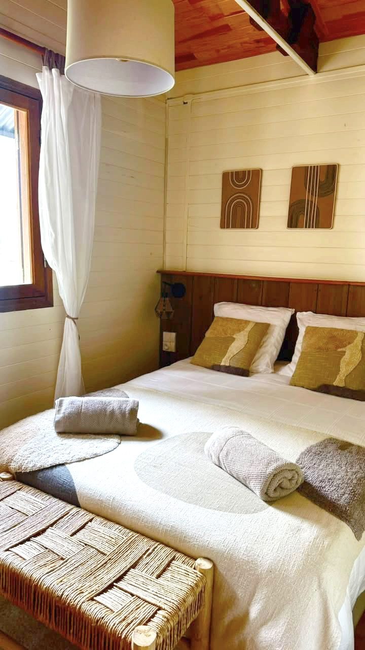 Vue d'ensemble de la première chambre double du Chalet Des Sens à Cilaos, lambris clair et linge de maison fourni